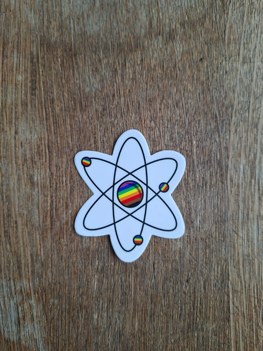 Atom symbol sticker with rainbow colors on a wooden surface