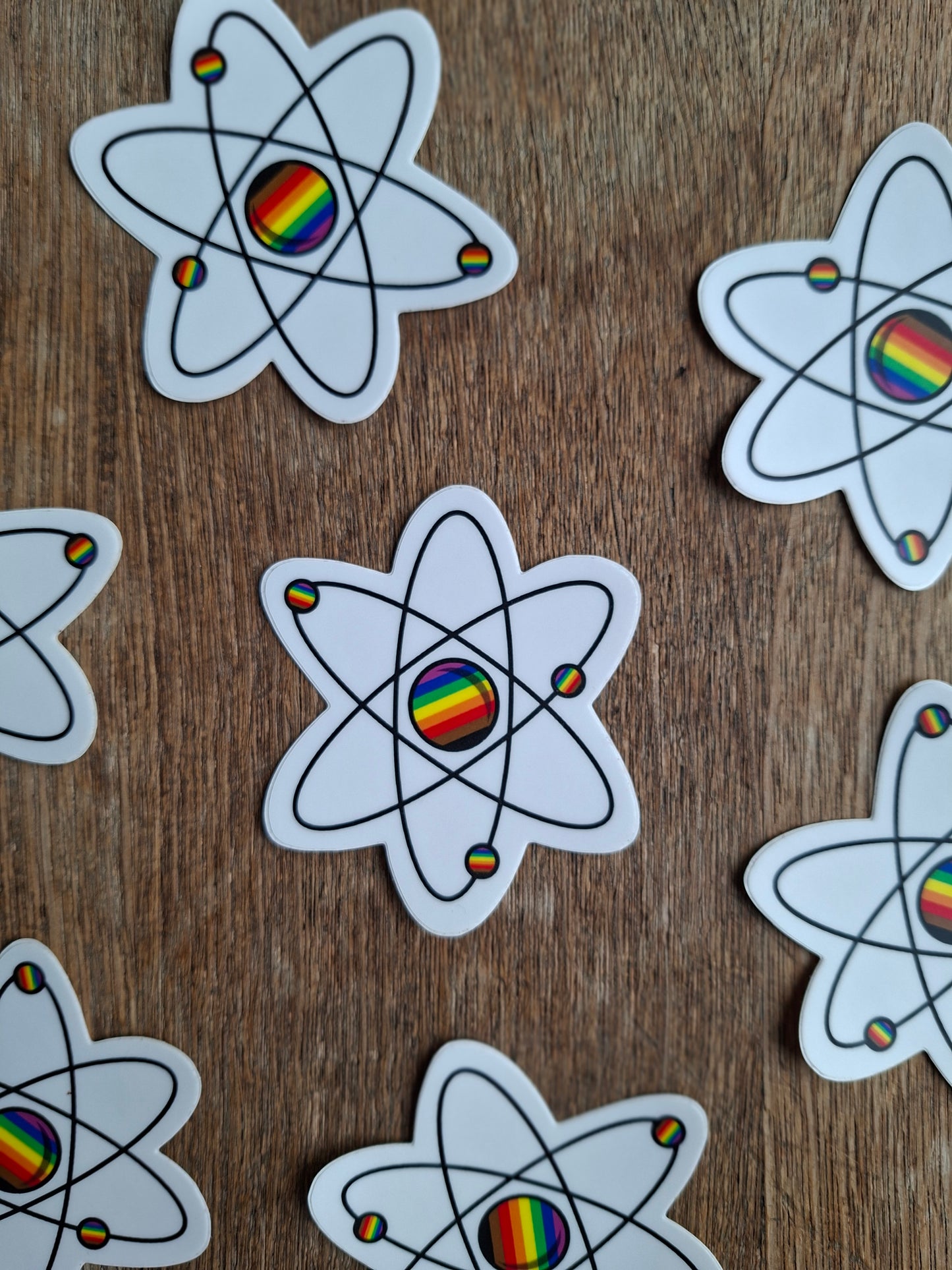 Atom symbol stickers with rainbow centers on a wooden surface
