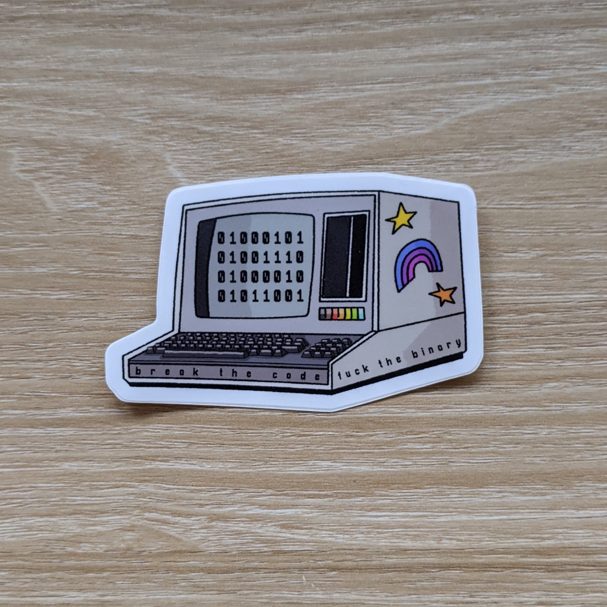 An image of a sticker with a retro computer displaying binary code, with a couple stickers on the side and the words along the bottom.